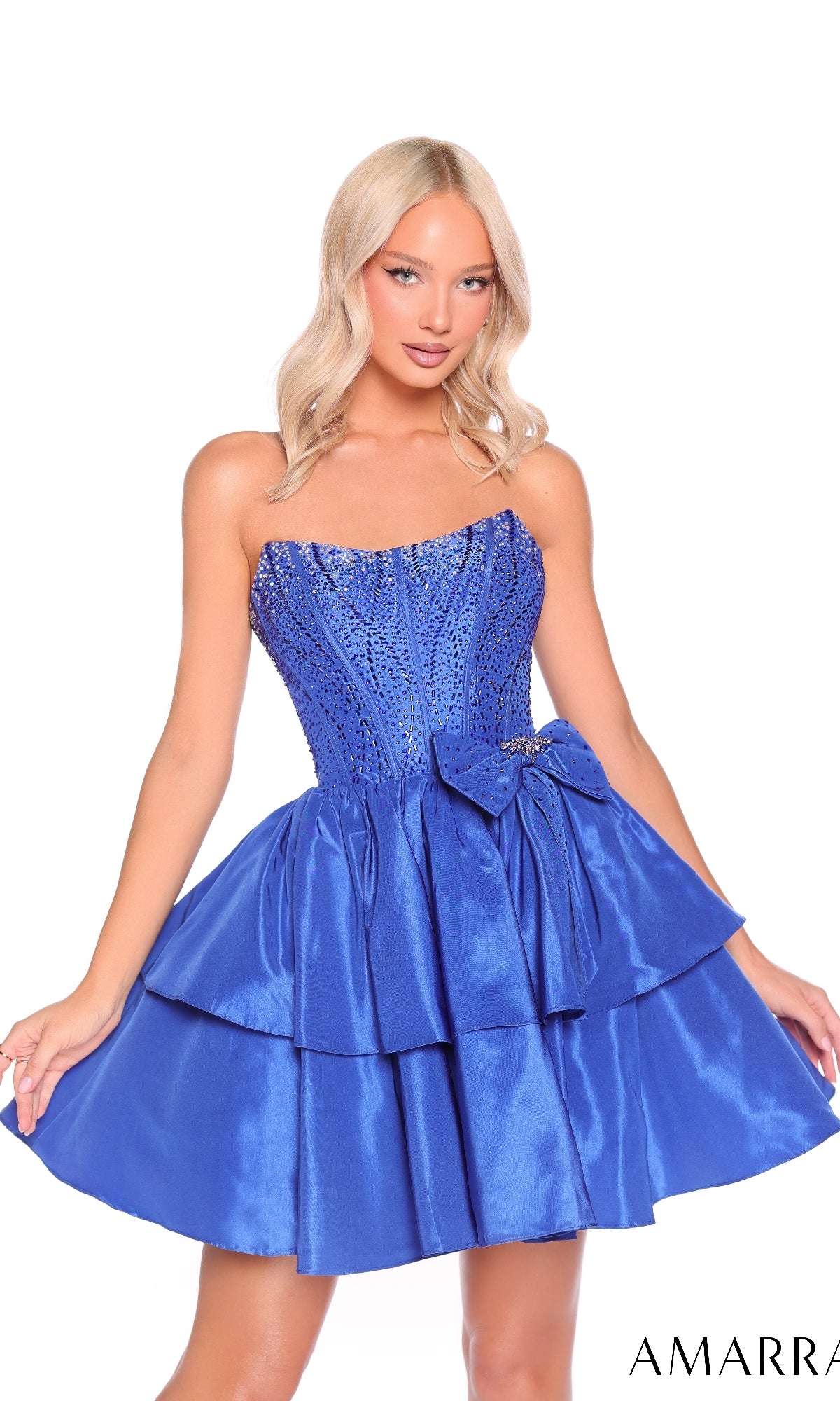 A woman wears the Strapless Short Ruffled Hoco Dress Amarra 88912 in royal blue, featuring sequins, a layered skirt, and a decorative waist bow.